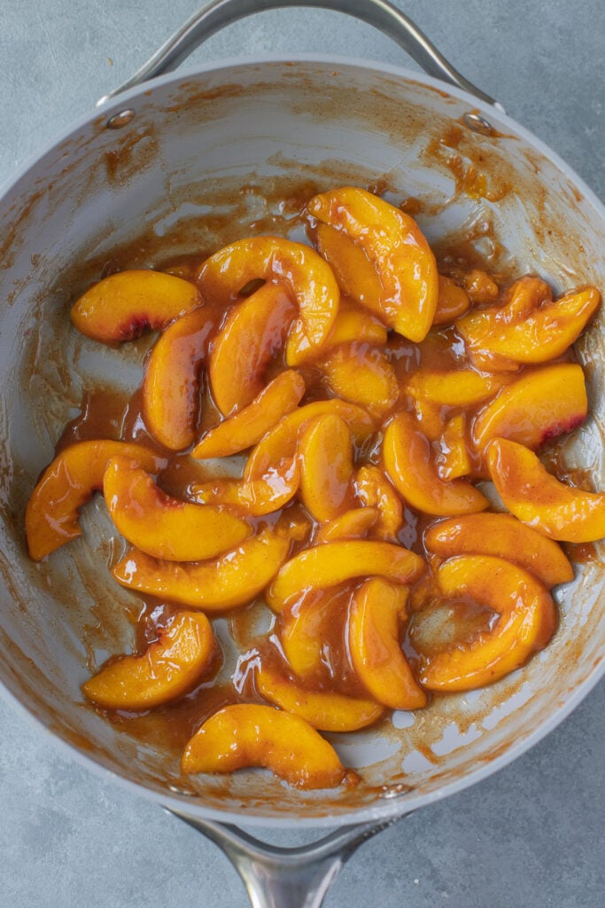 Fresh peach pie filling in a grey skillet.