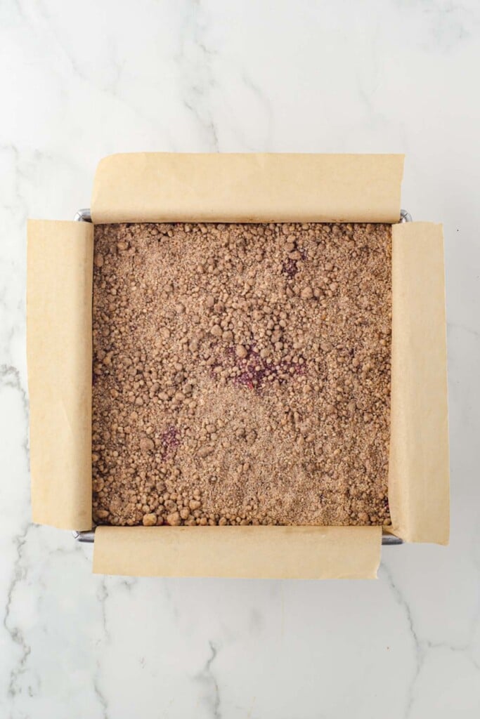 Unbaked streusel topped dessert bars in a square baking pan, viewed from overhead.