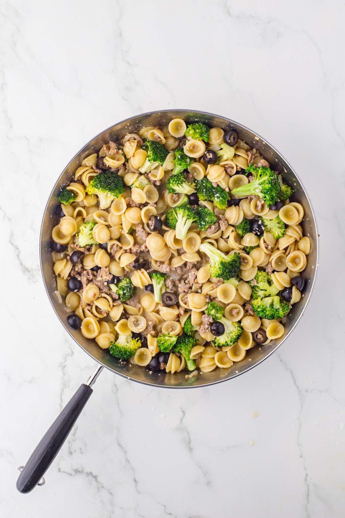 Italian sausage broccoli pasta dinner in a large skillet, as seen from overhead.