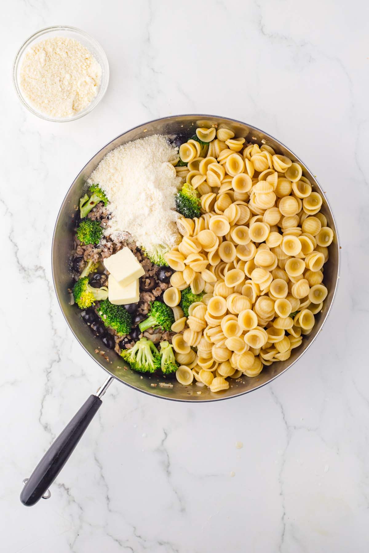Cooked orecchiette with sausage and broccoli in a skillet, viewed from overhead.